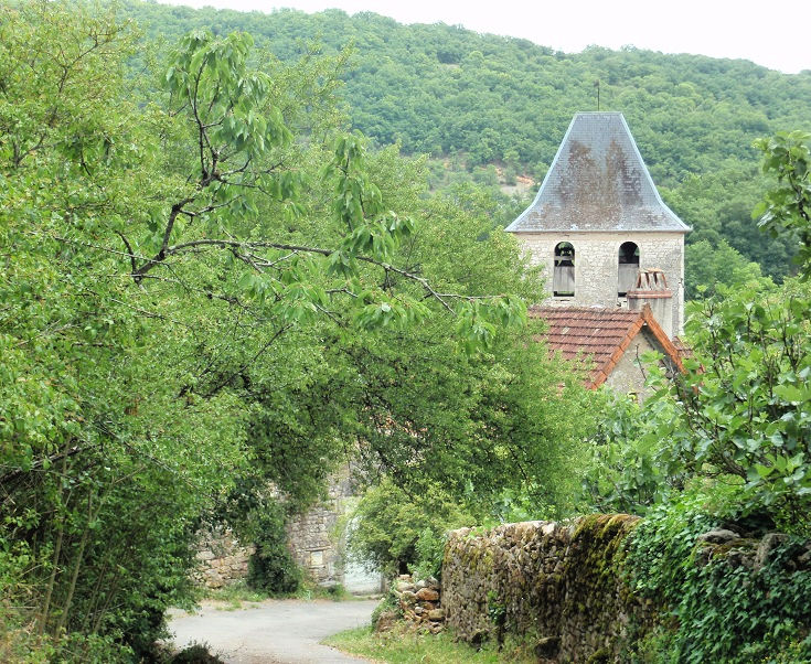Glimpses of the church steeple through the trees in Corn, France