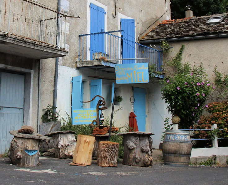 A small store with bright blue doors and shutters sells produce made from honey