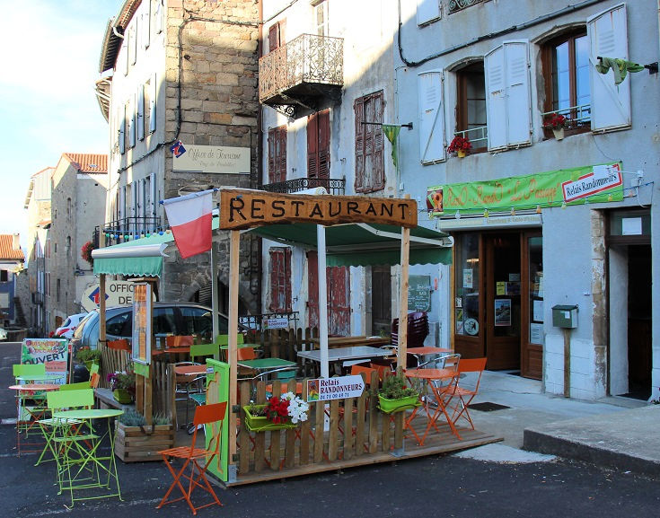 Café Relais Randonneurs decorated with orange and lime green tables and chairs set on a small terrace under a sheltered awning